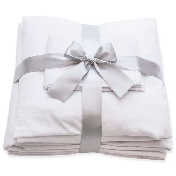 A neatly folded Berry Compliant Pillowcase USA Bedding is tied with a silver satin ribbon and bow, with a pillowcase placed on top. Made in USA.