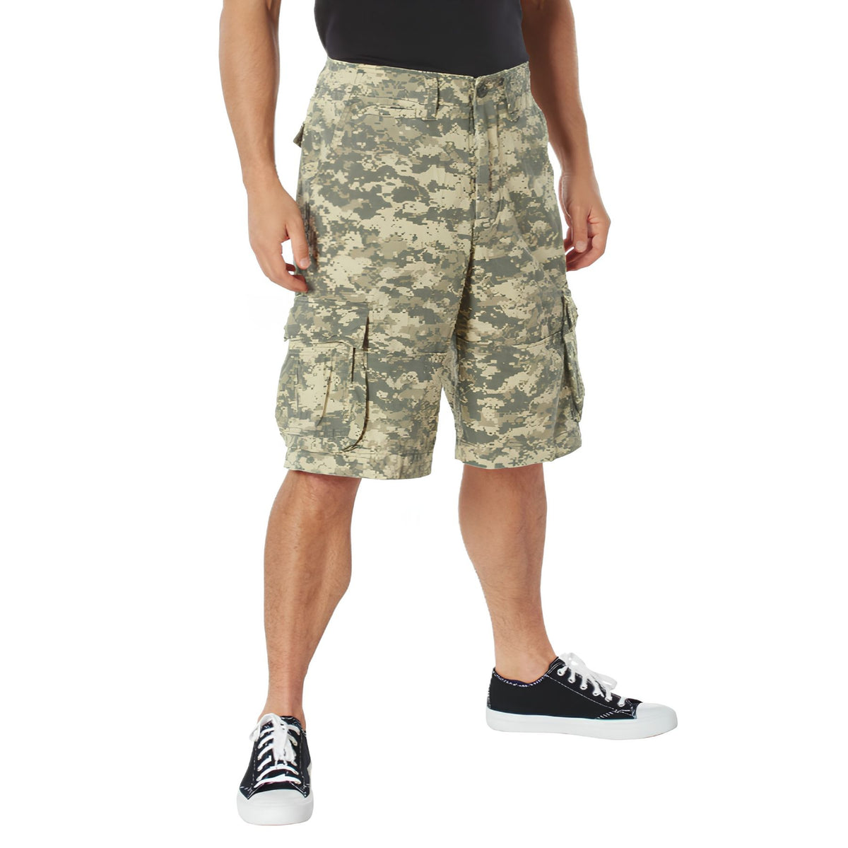 A person wearing Rothco Vintage Infantry Utility Cargo Shorts, a black shirt, and black low-top sneakers with white soles stands against a white background.