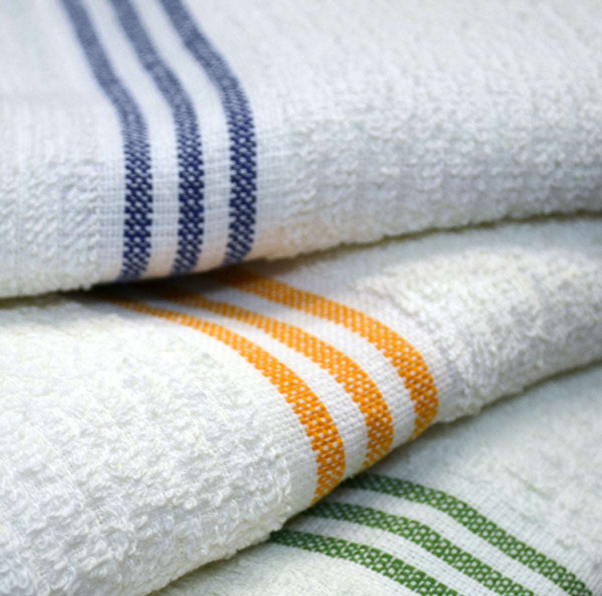 Three White Oxford Three Stripes Pool Towels from Ganesh Mills are stacked, each featuring blue, gold, and green stripes near the edge—perfect for anyone needing bulk pool towels.