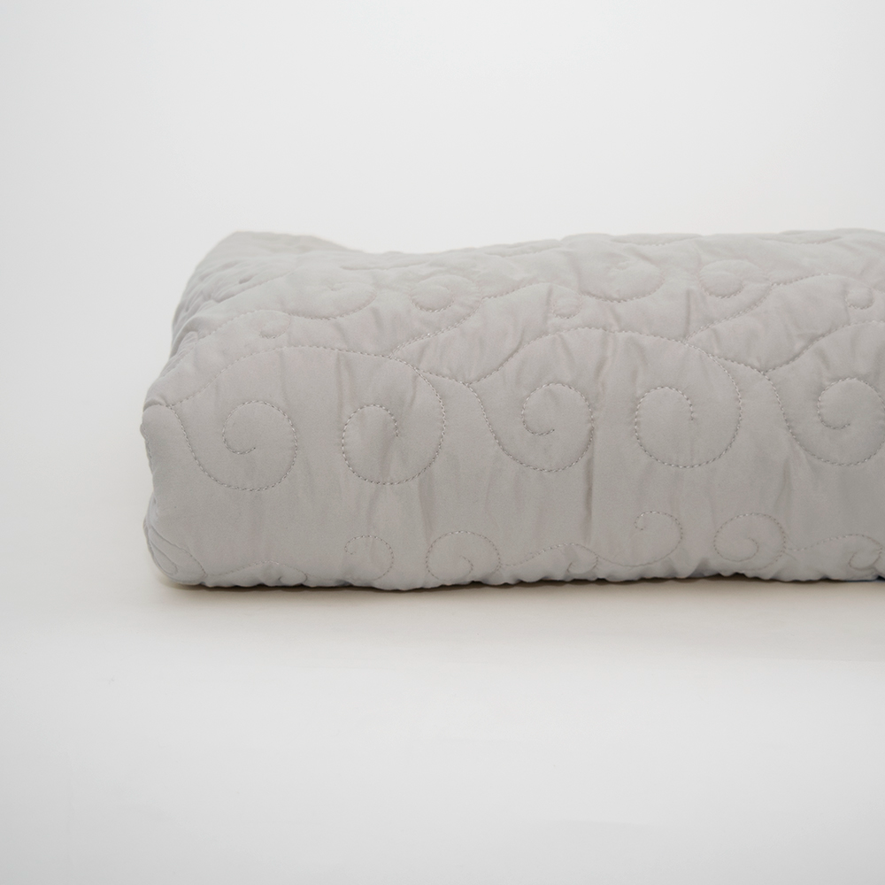 The Calderon Textiles Ascent Standard Bedspread is a folded light gray quilted cover with a subtle swirl stitch pattern, shown on a white background. Ideal for style and comfort in any space, it’s perfect for long-term care or everyday use.