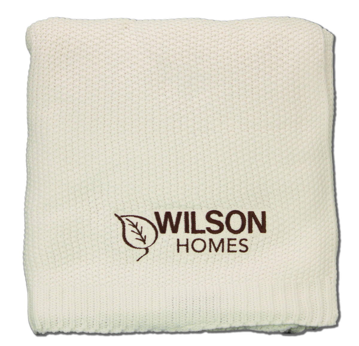 The Aliehs Crochet Knit Throw by Pro Towels is a cream-colored, folded blanket with Wilson Homes and a brown leaf logo embroidered, offering a stylish wholesale option.