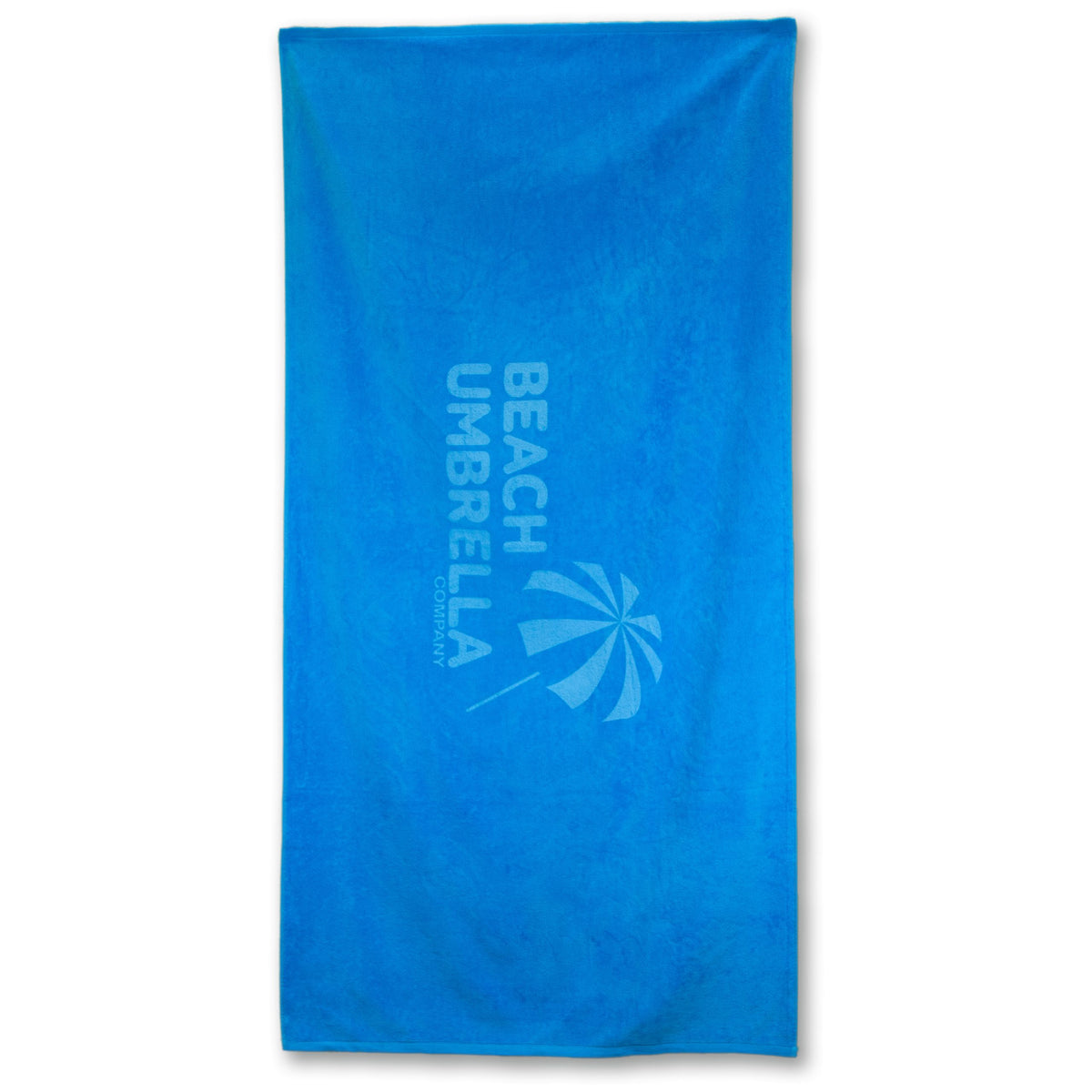 The Beach Towel - Platinum Collection by Pro Towels is a rectangular, heavyweight blue cotton towel featuring BEACH UMBRELLA COMPANY and an umbrella graphic printed vertically in a lighter blue shade.