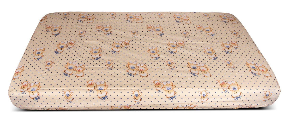 The KSE Woven Crib Fitted Sheet - Printed Design is shown covering a rectangular mattress against a white background, featuring beige fabric with small blue dots and cartoon teddy bears wearing blue hats and scarves.