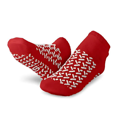 Two red KSE Fall-Risk Slipper Socks are shown, featuring white grips for safety—one upright and one flat to display the non-slip pattern, ideal for fall prevention in hospitals.