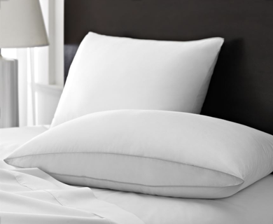 Two plush Pillow Glamour Down Alt Pillows by 1Concier rest on a neatly made bed with white sheets. A lamp and a dark headboard are visible in the background, creating a clean and cozy bedroom atmosphere.