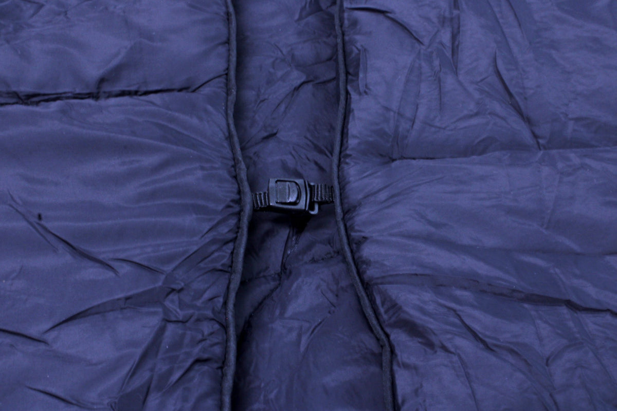 A close-up of a dark blue insulated jacket with a black plastic buckle highlights its texture—ideal to pair with your Pro Towels Lofthouse Camping Blanket for outdoor adventures.
