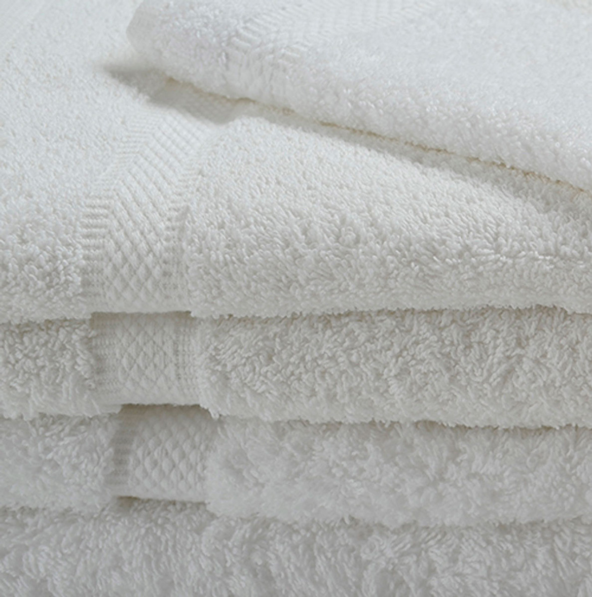 A close-up of several neatly folded Ganesh Mills Bath Towel - White Oxford Imperiale Towels stacked together, highlighting their soft ringspun cotton texture and elegant border patterns.