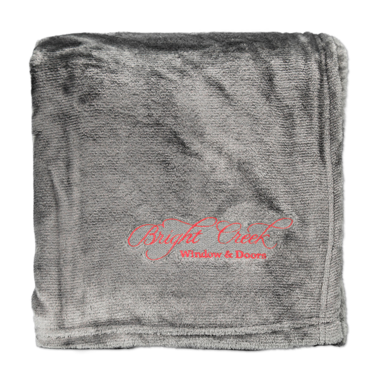 The Pro Towels Laden Comfort Throw Oversized, folded in gray and custom embroidered with “Bright Creek Window & Doors” in red script, makes an ideal corporate gift blanket.