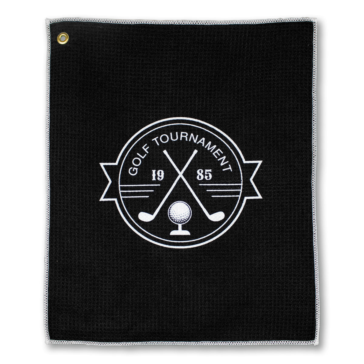 The Pro Towels Microfiber Waffle Small Golf Towel features a black waffle weave, a white embroidered crossed golf clubs and ball logo with "GOLF TOURNAMENT 1985" text, plus a metal grommet in the top left for easy attachment.