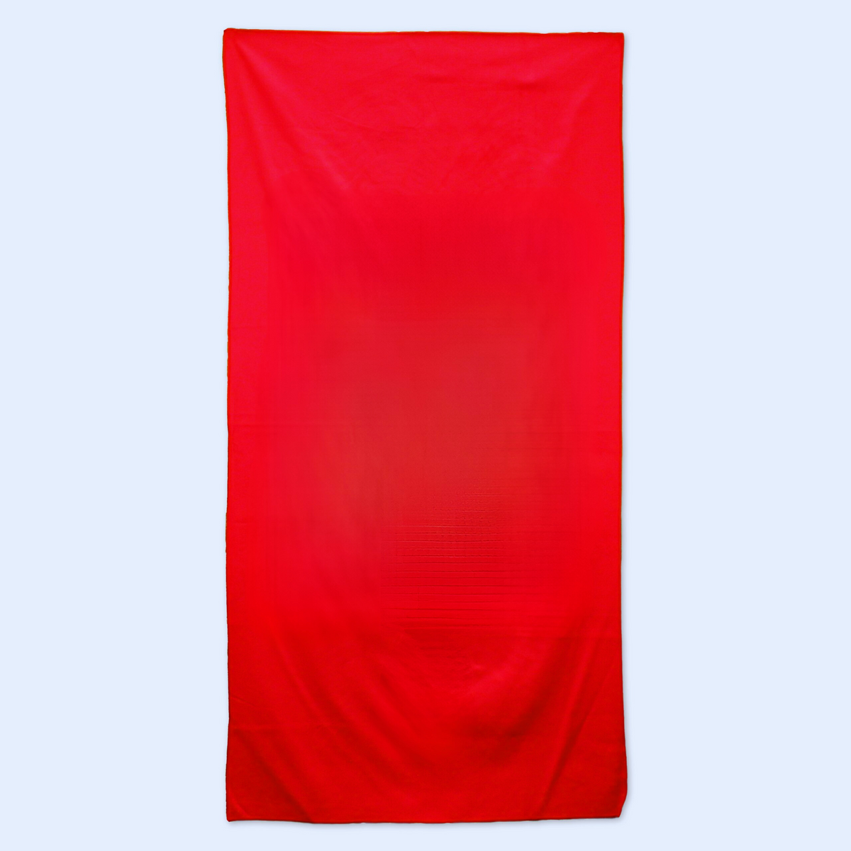 A large rectangular red Pro Towels Microsuede Beach Towel is displayed on a light grey background, featuring soft folds and gentle shading on its surface.