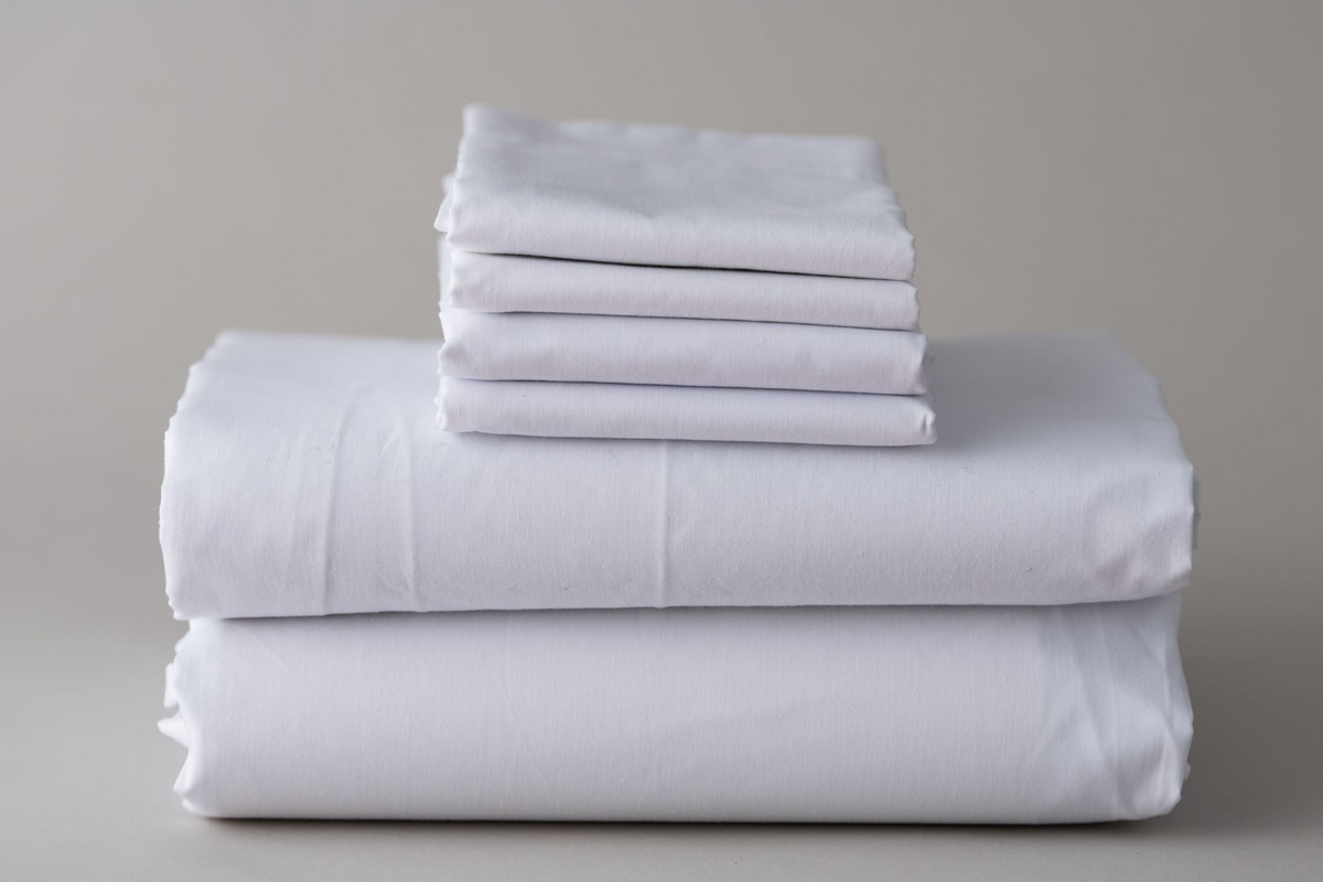 A neatly folded stack of Thomaston Mills Pillowcases - Thomaston Brand Single Pick Percale rests on a plain light gray surface against a neutral gray background.