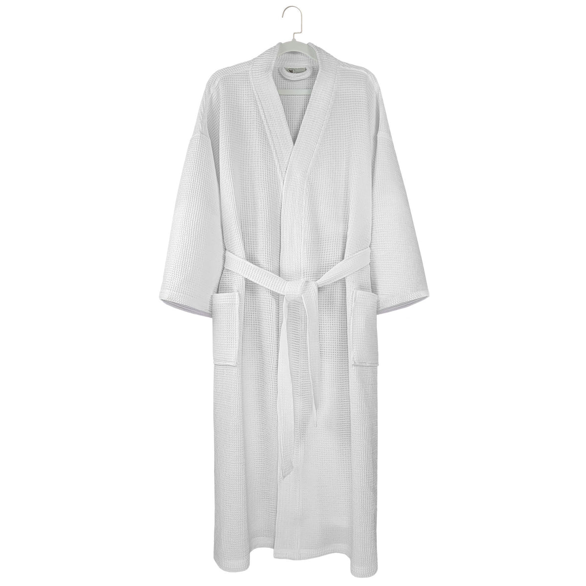 The Ganesh Mills Oxford Honeycomb Waffle Bathrobe in white, featuring long sleeves, front pockets, and a belt, hangs on a hook against a plain white background.