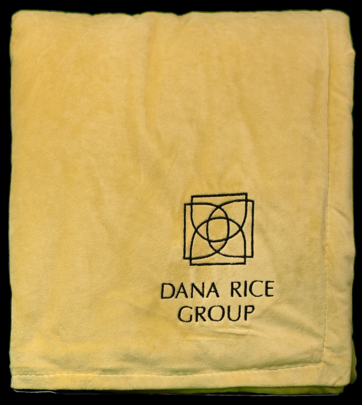 A folded yellow Pro Towels Rural Llama Throw with the Dana Rice Group logo and name custom embroidered in black on one corner.