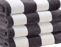 Four Oxford Playa 2x2 Cabana Pool Towels by Ganesh Mills, featuring wide black and white stripes, are stacked neatly on top of each other.