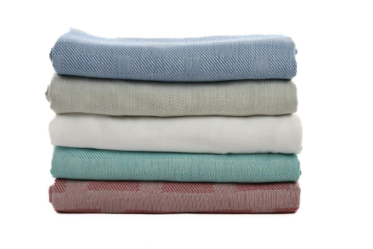 A stack of five KSE EverLast Spread Blankets in pastel blue, gray, white, green, and pink is neatly folded and arranged on a white background.