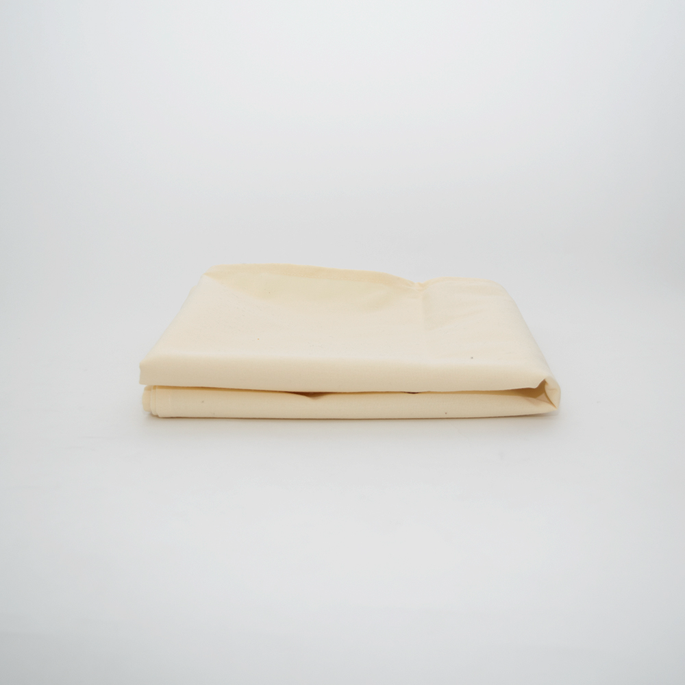 The Calderon Textiles Prisma Table Cloth RFID Chip, a durable and colorfast light beige fabric, is neatly folded on a plain white surface with a softly lit, minimal background.