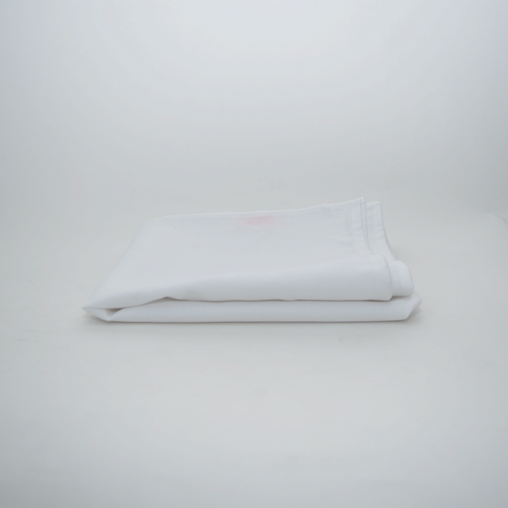 A neatly folded white Prisma Table Cloth by Calderon Textiles, renowned for durability and stain resistance, is placed on a plain light-colored surface with a minimalistic background.