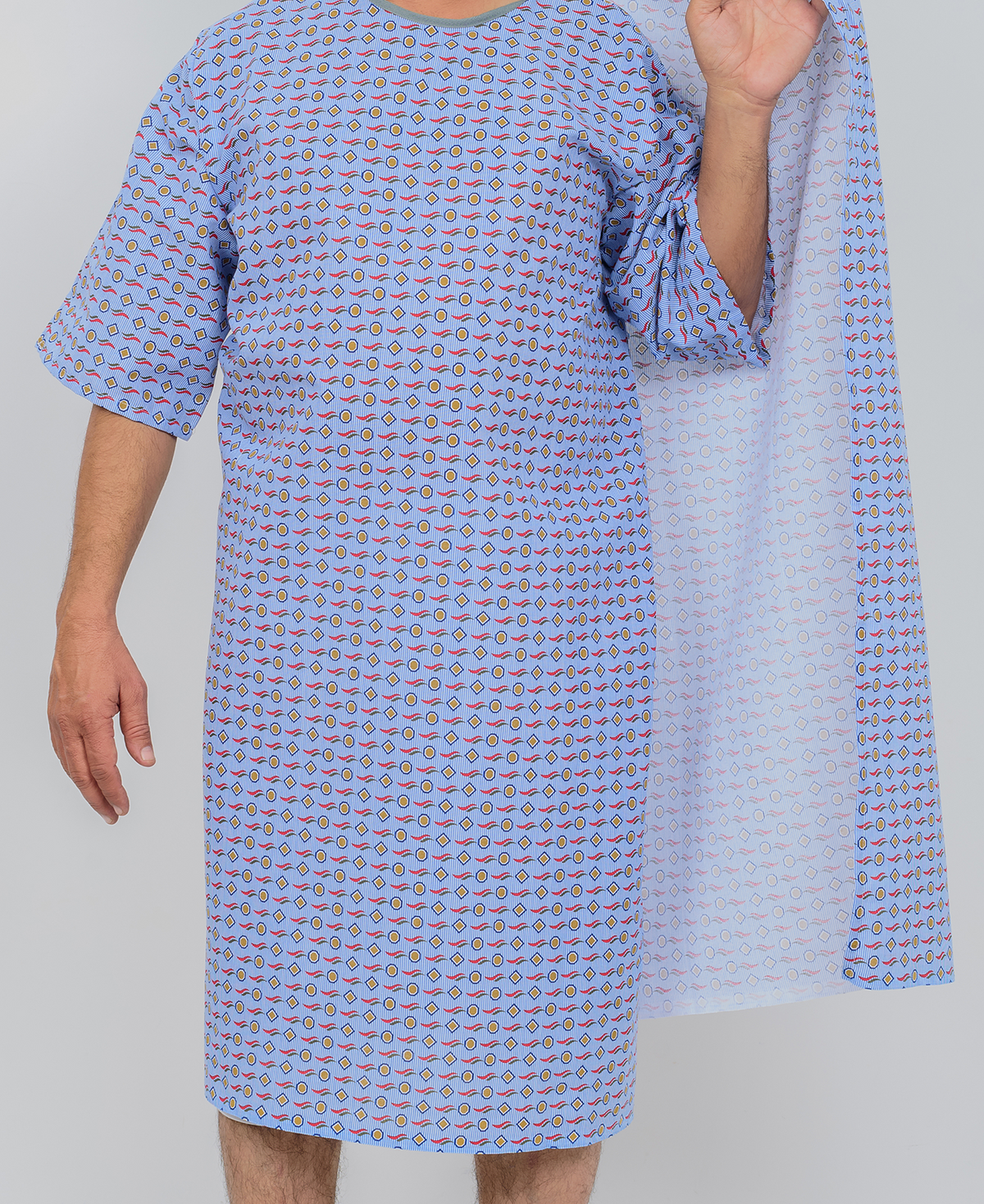 A person wears a KSE Three-Arm hole Gown with short sleeves and small colorful patterns, holding one side open; their face is out of frame, and the plain background is light gray.