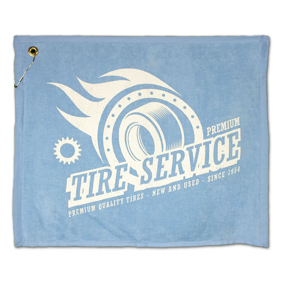 The Pro Towels Jewel Collection Soft Touch Golf Towel in light blue features a tire, gear, and flames graphic with "Tire Service: Premium Quality Tires - New and Used - Since 1954" plus a brass grommet and metal hook at the top left corner.
