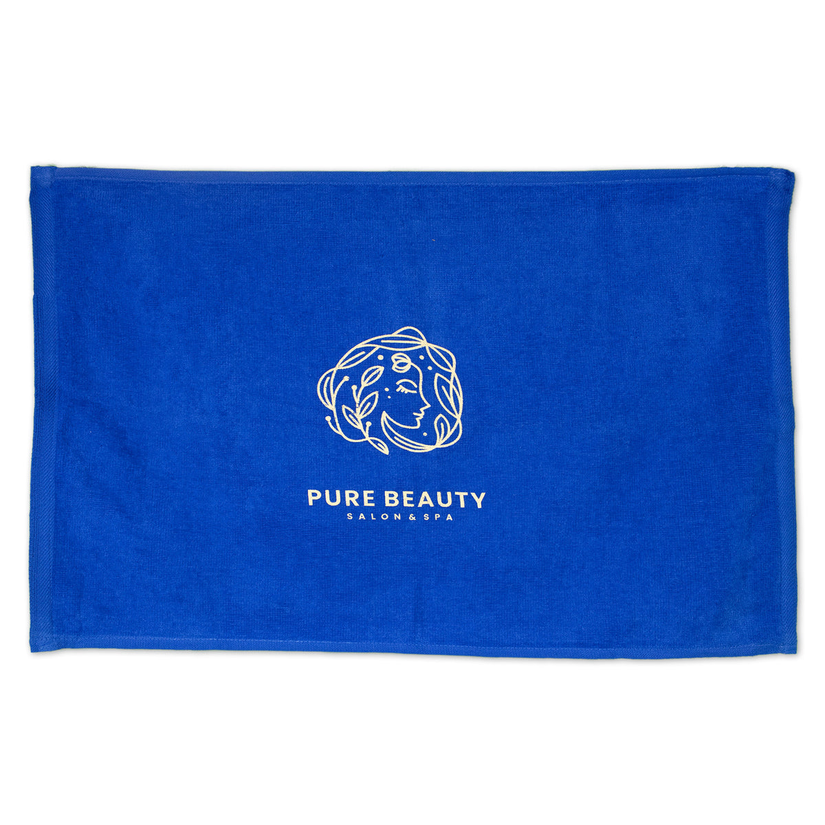 A Pro Towels Diamond Collection Sport Towel in royal blue with custom "PURE BEAUTY SALON & SPA" embroidery and a minimalist white line drawing of a woman's face with flowing hair at the center.