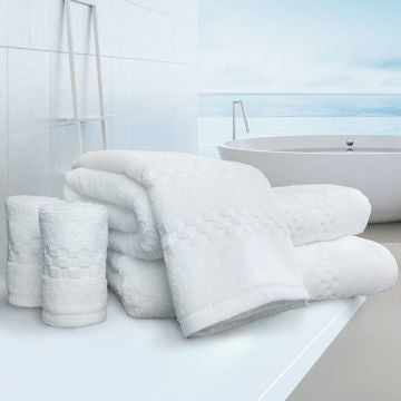 A stack of Ganesh Mills Bath Sheet / Pool Towel - White Oxford Viceroy Towels sits on a white counter in a modern bathroom with water views, evoking the comfort and luxury of hotel-quality towels.