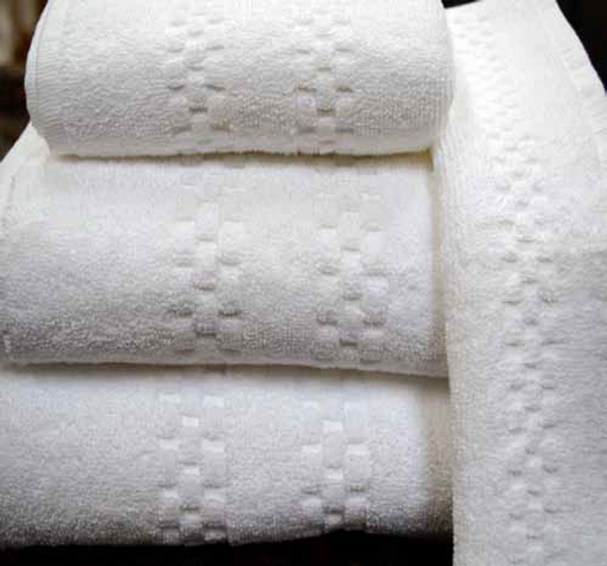The Ganesh Mills Bathmat - White Oxford Viceroy Towels features a subtle square and linear pattern, adding understated luxury to any space when placed on a dark surface.