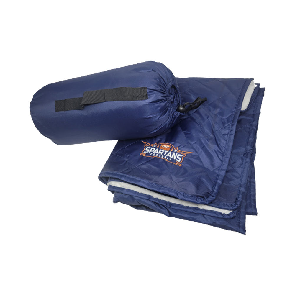 The Pro Towels Waterproof Sherpa Blanket in blue features custom Spartans logo embroidery and comes partially folded next to a matching blue drawstring bag with a black handle.