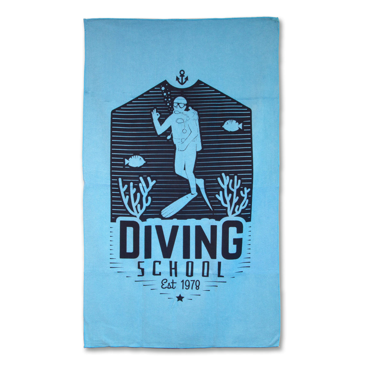 The Pro Towels Waffle Weave Beach Towel is blue and features a scuba diver underwater with fish, coral, and “Diving School Est 1978” in dark blue.