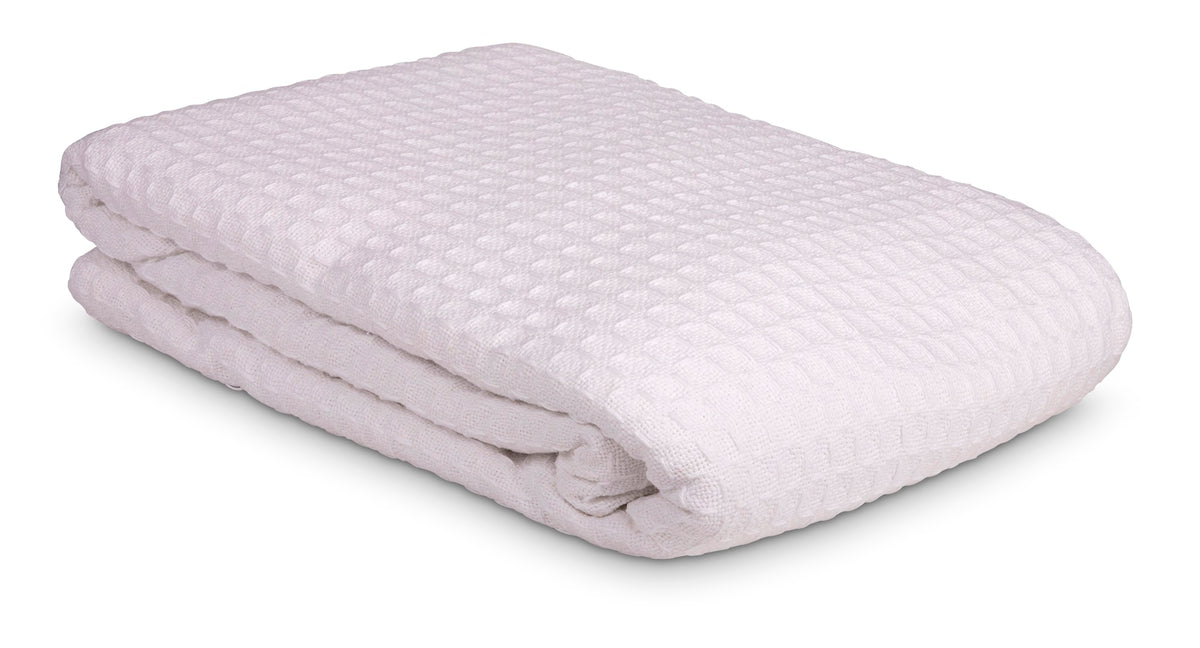 A KSE Waffle Weave Blanket in white, featuring a textured waffle-like pattern, is neatly folded and displayed against a plain white background.