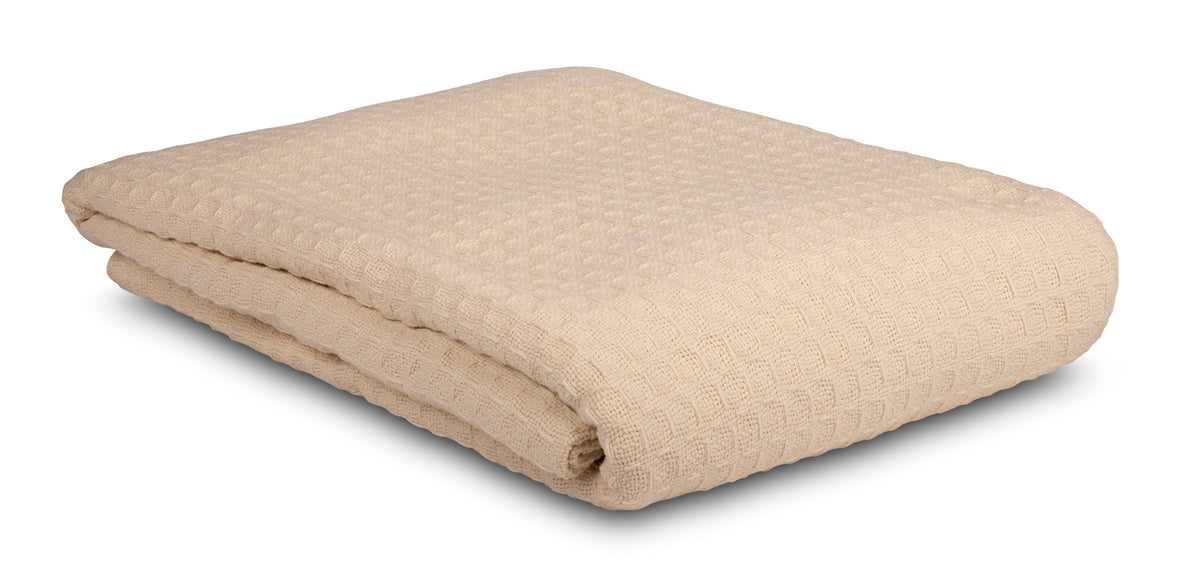 A folded beige KSE Waffle Weave Blanket, made from soft cotton, is displayed on a white background—ideal for those seeking quality cotton blankets or bulk wholesale options.