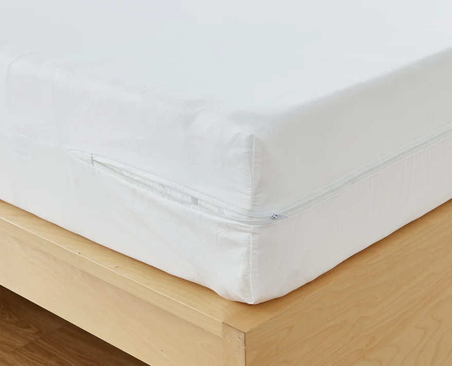 Close-up of a mattress on a wooden frame, covered with the Bargoose AllergyCare Cotton Zippered Mattress Encasement—16 Deep. The partially open zipper shows the mattress edge and offers added bed bug protection.
