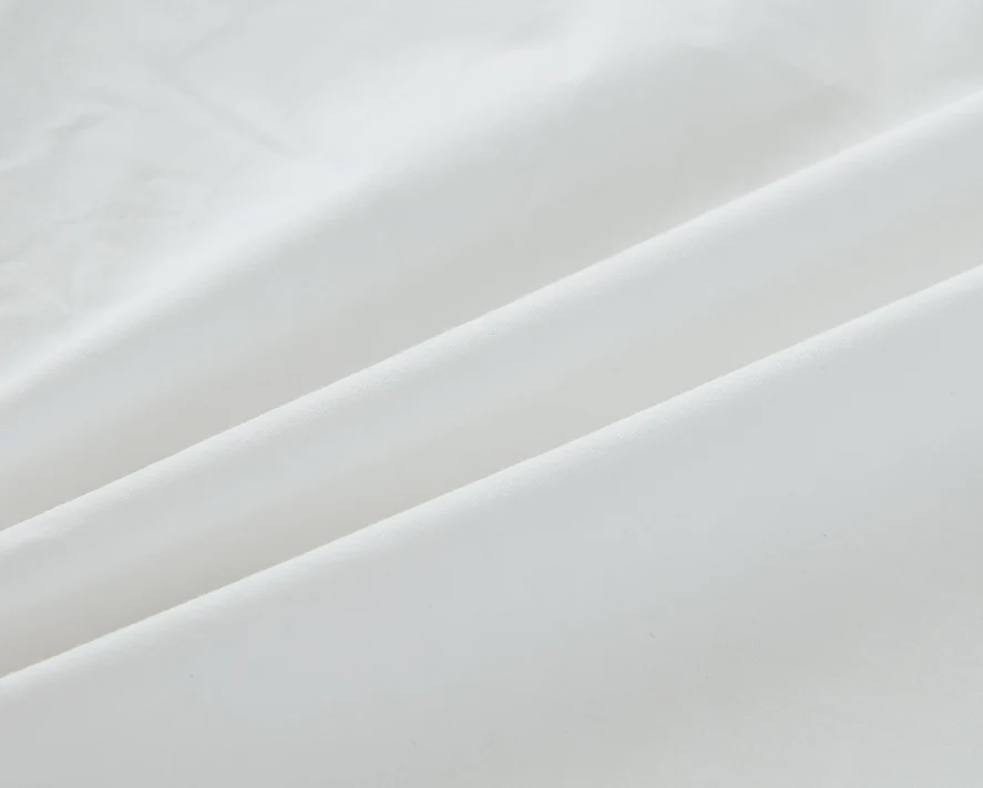 Close-up of the Bargoose AllergyCare Cotton Zippered Mattress Encasement - 9 Deep, showing smooth, white cotton fabric with soft folds and creases for a calm, minimal look while protecting against bed bugs.
