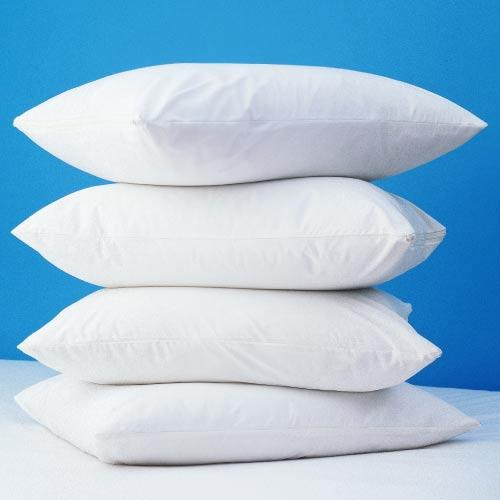 Four white pillows are stacked against a bright blue background, each protected by Bargoose AllergyCare Pristine® Allergen Barrier Zippered Pillow Covers for a cleaner, dust-free rest.