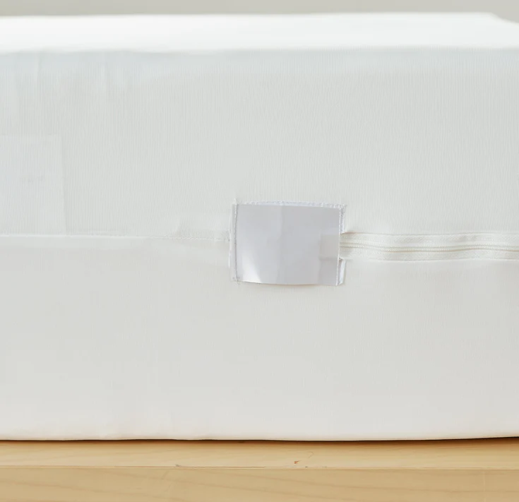 Close-up of the Bargoose 6 Gauge Vinyl Zippered Cover, designed for mattresses up to 12 deep. A discreet side zipper and smooth white surface provide protective coverage with a clean, stylish look on light wood.