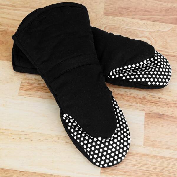 A Ganesh Mills Oxford Oven Mitt, 13" in black with white dots, is placed on a light wooden surface.