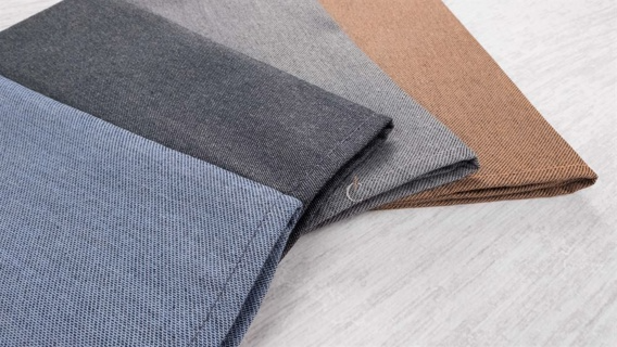 Four Napkin Craft Collection 100% Poly Smoky Blue swatches by 1Concier are neatly arranged side by side on a light wooden surface, showcasing perfect options for yarn-dyed napkins.