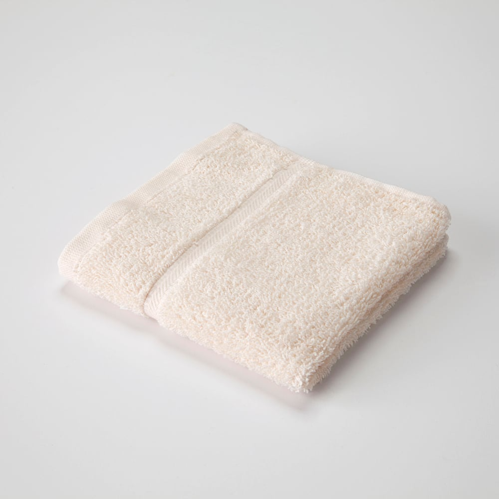 A neatly folded, light beige WestPoint Home Dobby Towel - Martex Sovereign with a textured surface and blended dobby ensemble is placed on a plain white background.