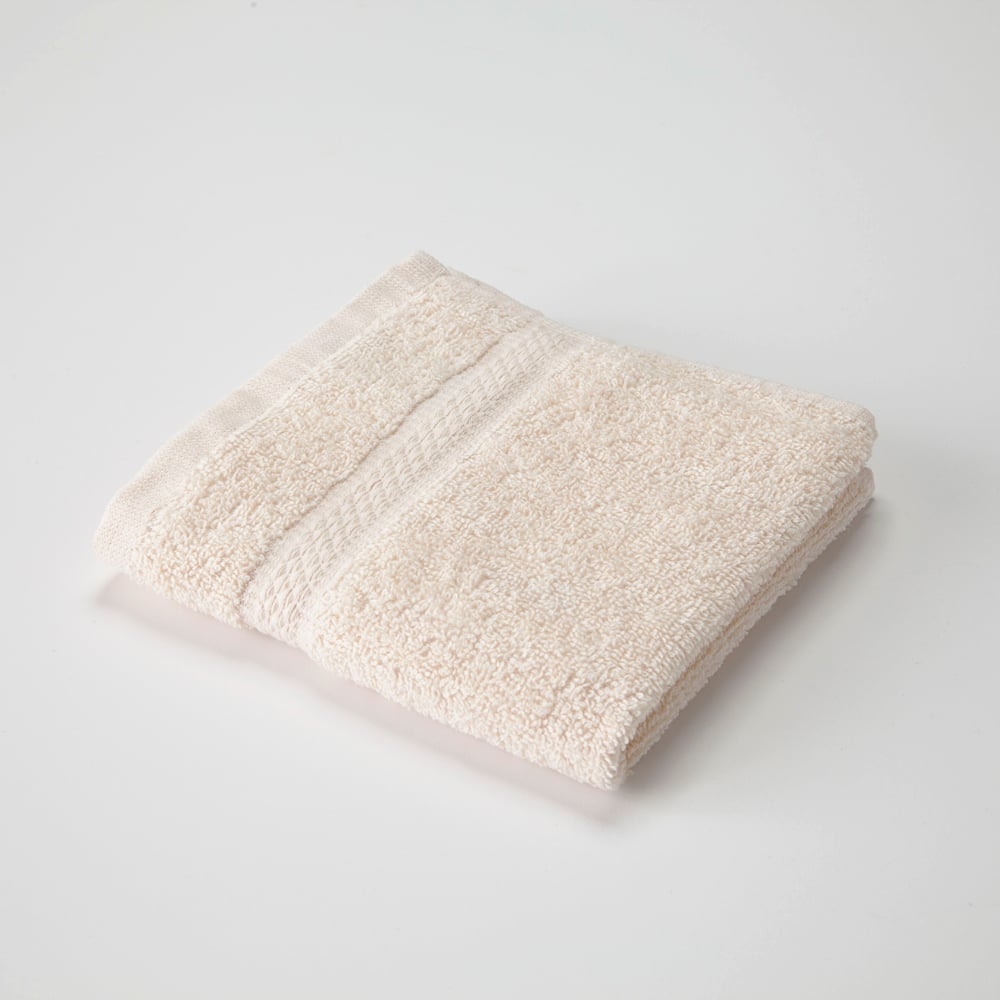 The WestPoint Home Martex Brentwood Dobby Towel is a neatly folded, light beige cotton/poly blend towel featuring a textured edge, displayed on a plain white surface.
