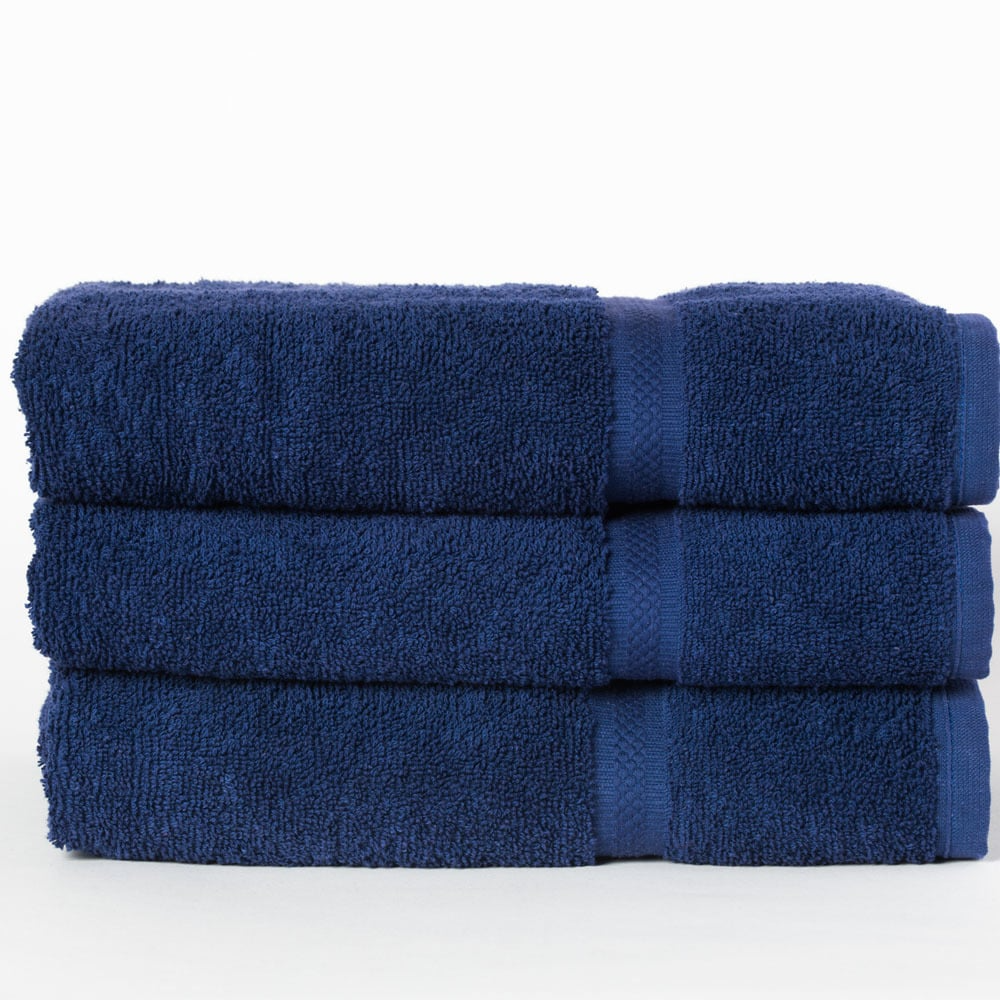 Three neatly folded, dark blue Dobby Towel - Martex Colors by WestPoint Home towels are stacked atop each other against a plain white background.