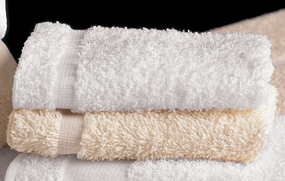 A close-up of two neatly folded Bath Towel - Martex - Cam Towels from WestPoint Home, one white and one beige, stacked against a dark background, highlighting their soft, premium hospitality quality.