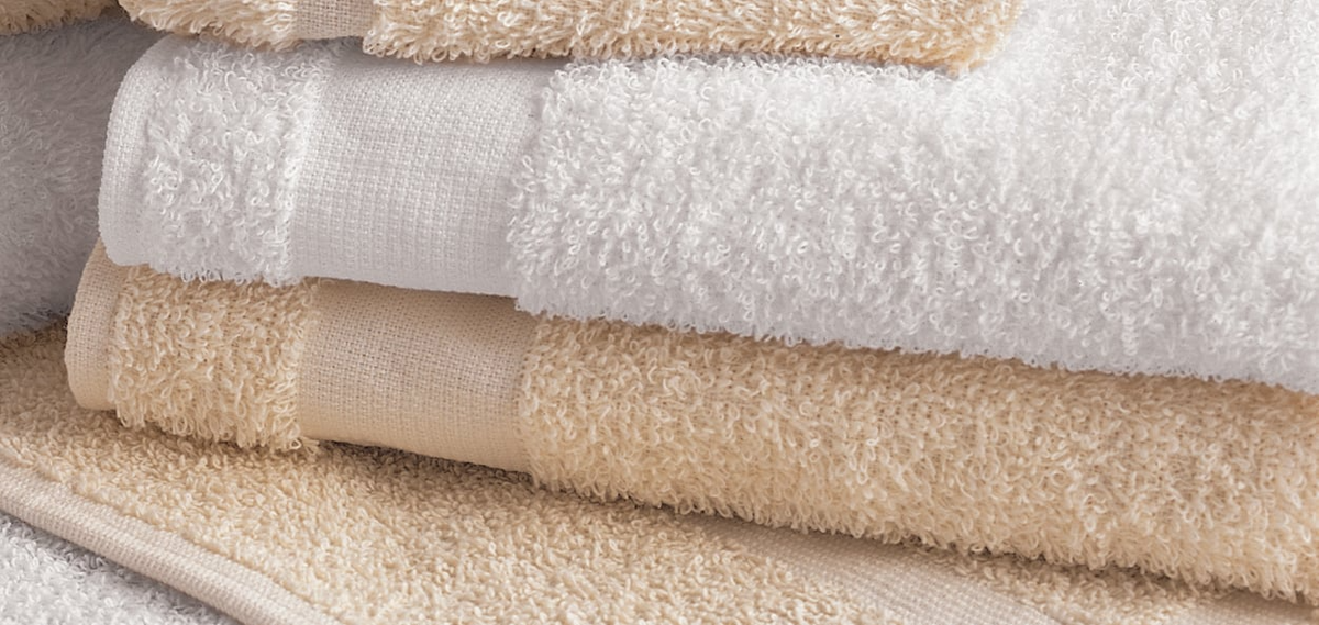 A close-up of neatly folded Martex Fingertip towels by WestPoint Home in white and beige, highlighting their soft, fluffy texture—ideal hospitality towels that deliver comfort and style.