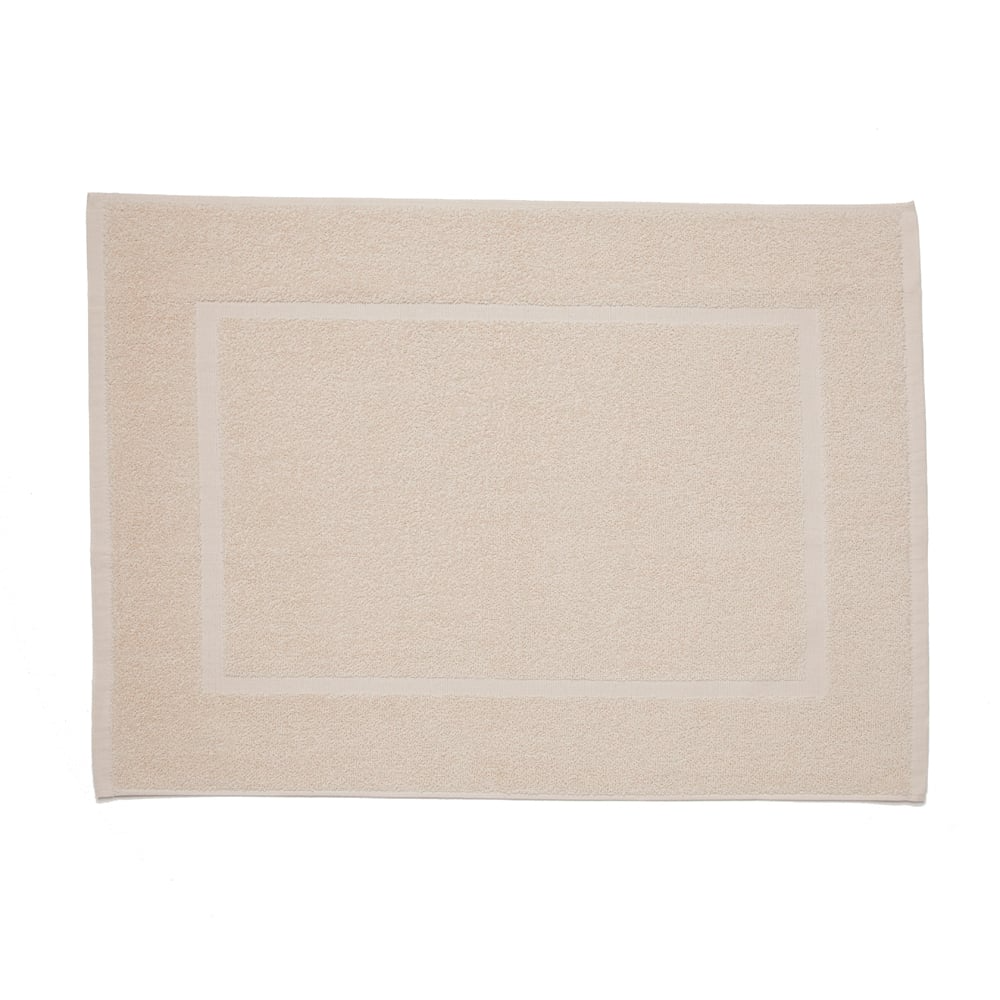 A rectangular beige bath mat with a subtle border accents WestPoint Home’s Martex Fingertip towels, shown on a white background.