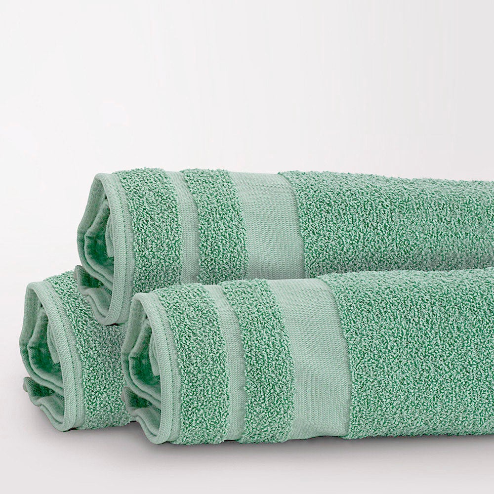 Three neatly rolled, light green Pool Towels from the Martex Cabana Collection by WestPoint Home, featuring textured and smooth stripes, are stacked in a pyramid shape against a plain white background.