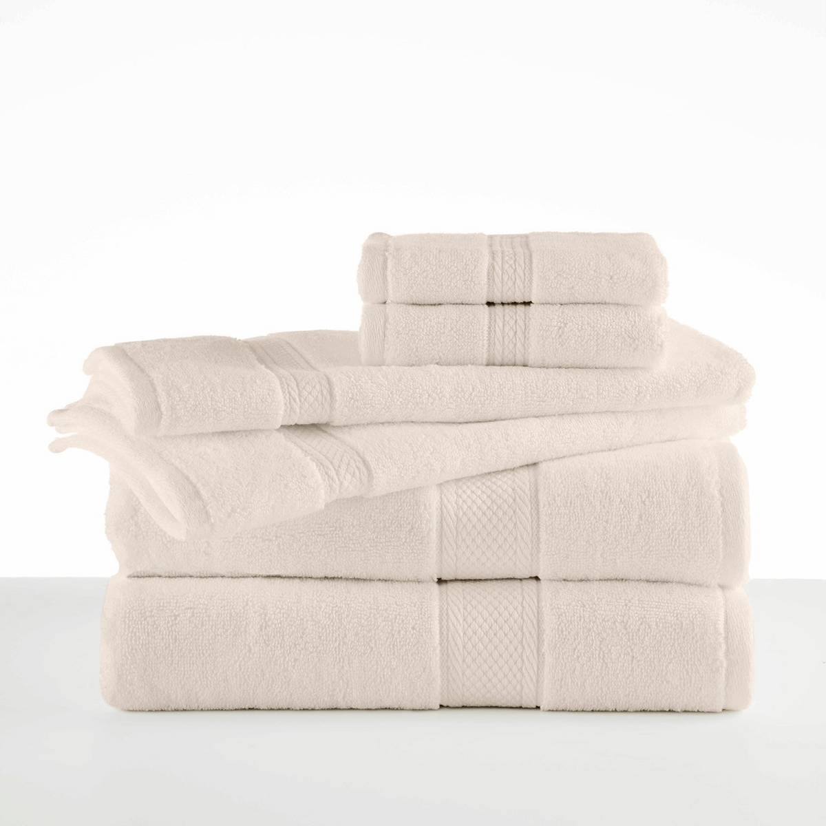 A neatly stacked set of soft, ivory Grand Patrician Suites Dobby Towels and washcloths by WestPoint Home arranged on a white surface against a plain background.