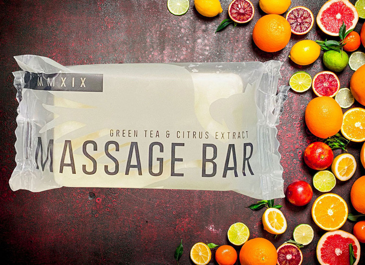 A Ganesh Mills Soap (Rectangle Shape) - Candy Wrap Embossed bar sits on a red surface next to sliced oranges, lemons, limes, and grapefruits.