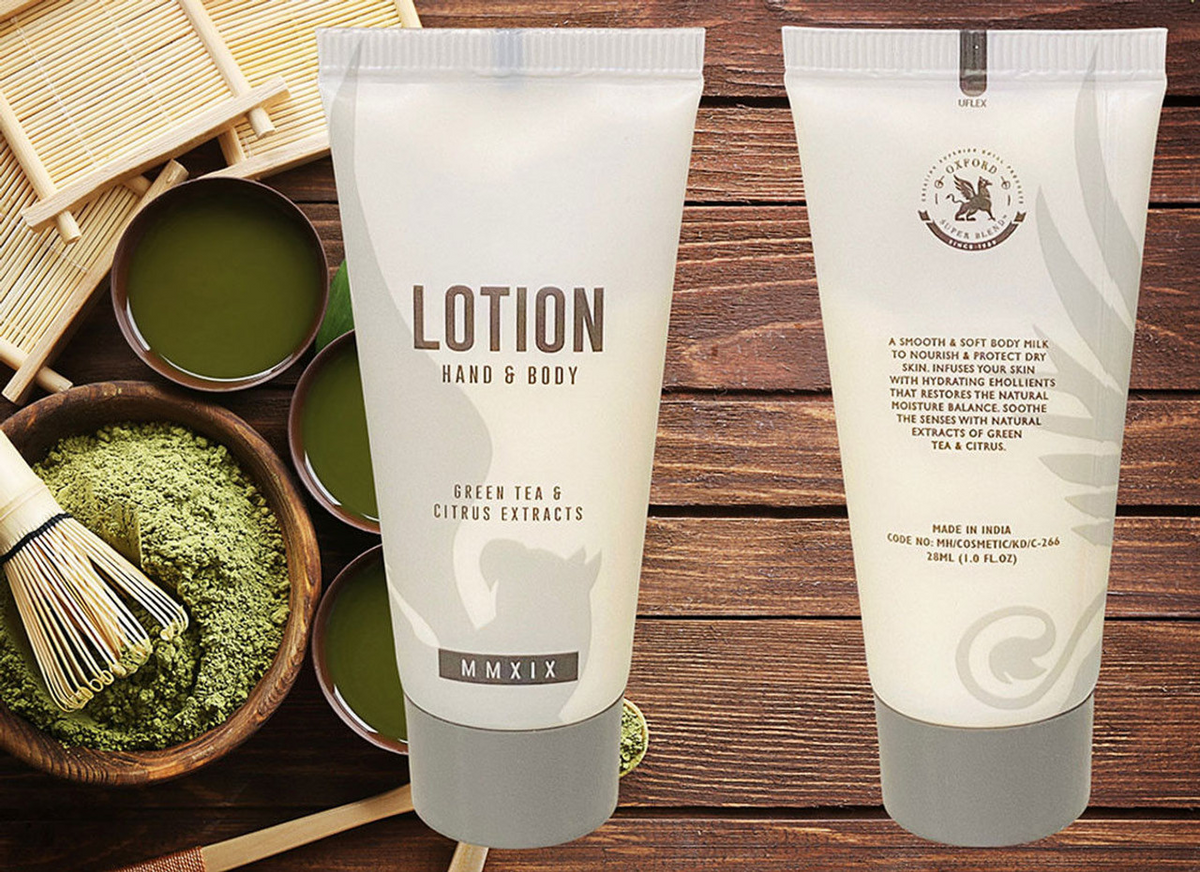 A Ganesh Mills Soap (Rectangle Shape) - Candy Wrap Embossed is shown front and back on a wooden surface with green tea powder, a bamboo whisk, bowls of green tea, and other premium hotel soap and amenity products.