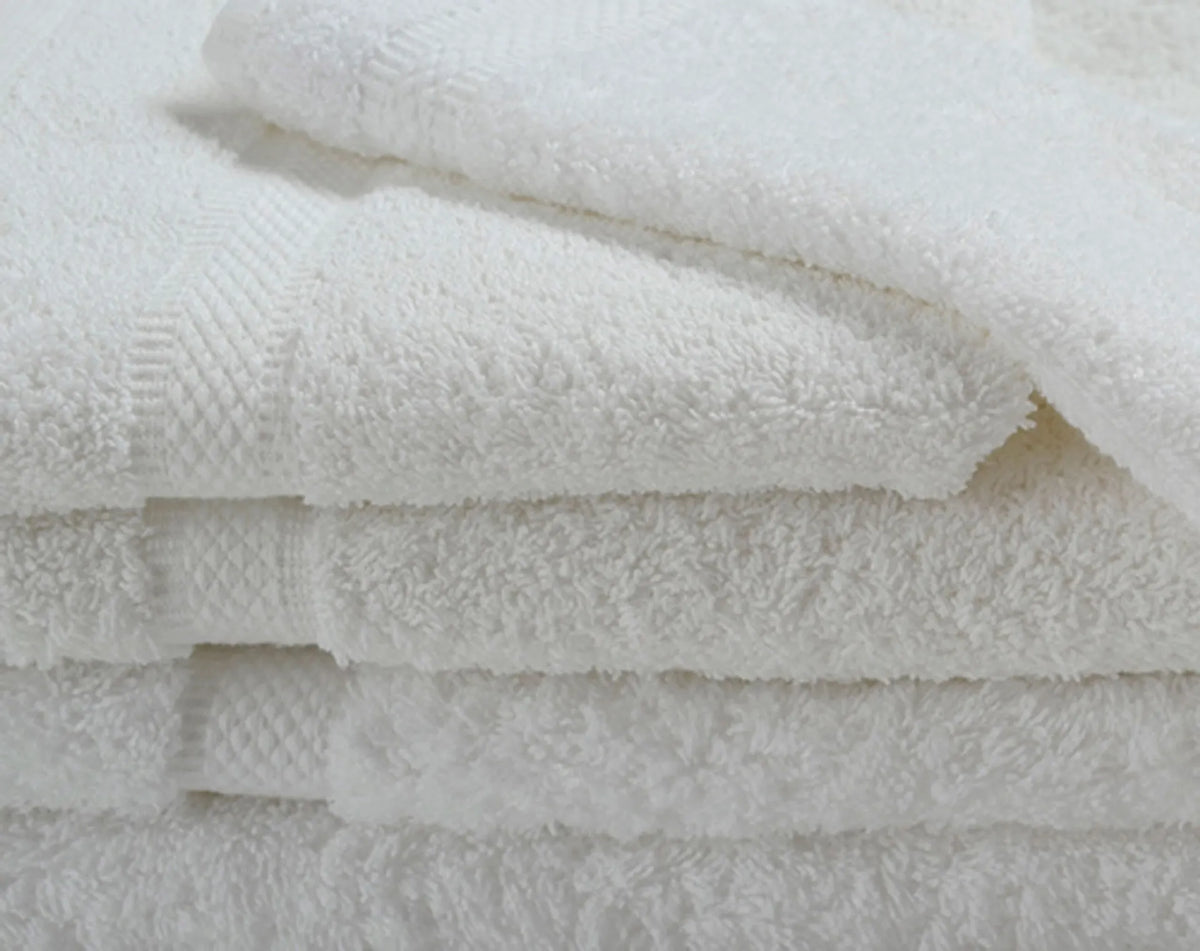 A close-up of four fluffy white towels from Ganesh Mills’ Washcloth - White Oxford Imperiale Max Towel Collection, showcasing their soft texture and subtle woven patterns.