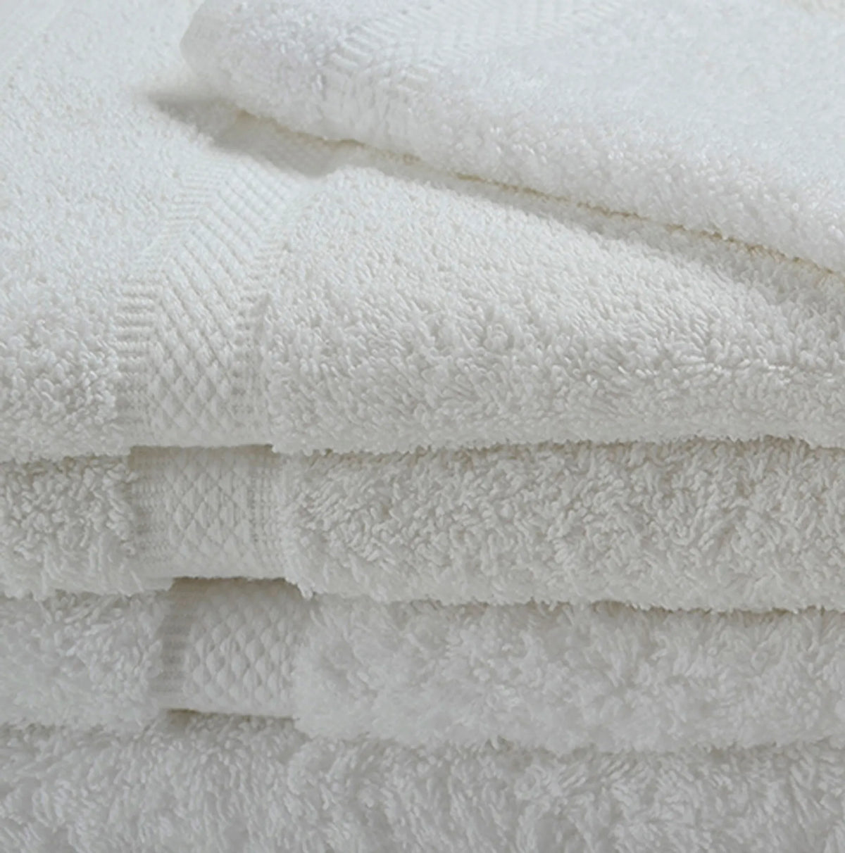 A close-up of Ganesh Mills Bath Towel - Double Dobby Oxford Imperiale towels, neatly stacked to showcase their soft ringspun cotton texture and subtle decorative borders.