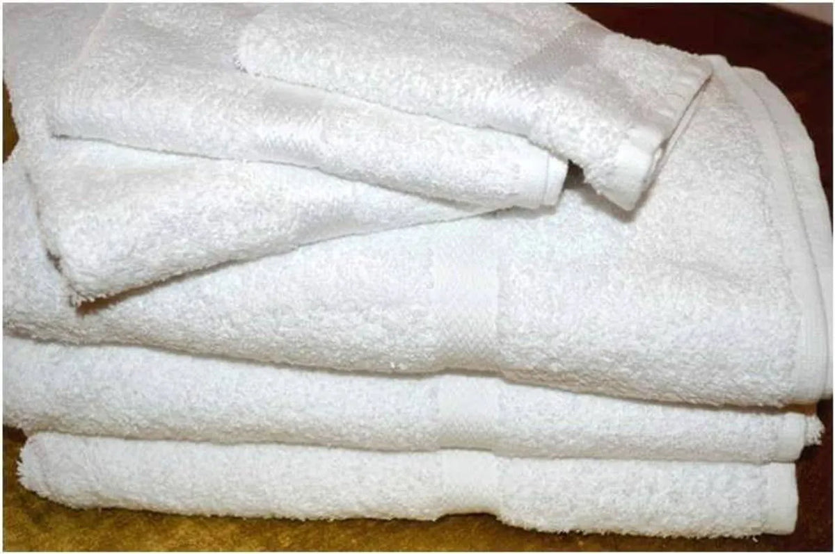 A neatly folded stack of Ganesh Mills Bath Sheet / Pool Towel - White Oxford Regale Towels rests on a brown surface, showcasing plush white cotton towels.