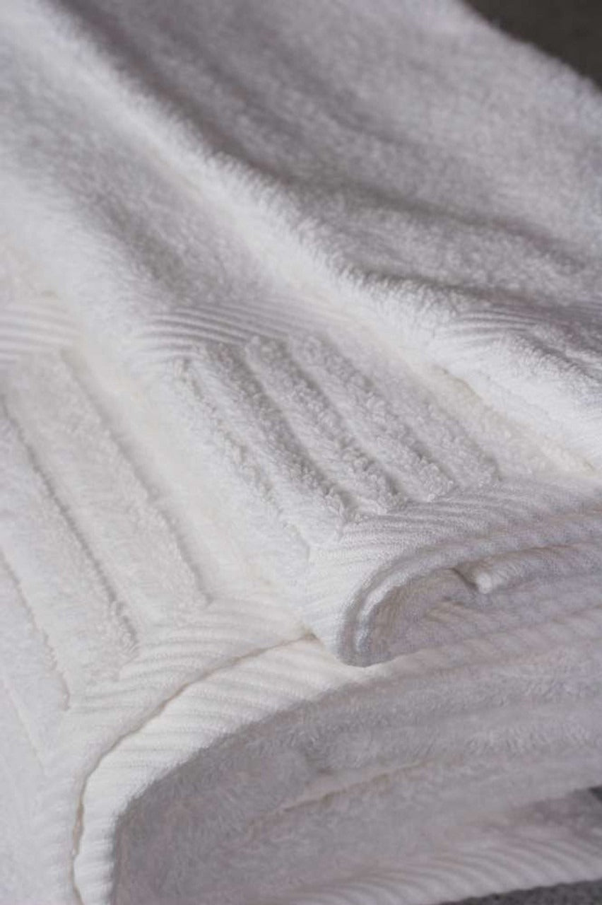 A close-up of Ganesh Mills’ White Oxford Signature Washcloth highlights its soft texture and subtle stripes—ideal for anyone craving the plush luxury of a high-end hotel towel.